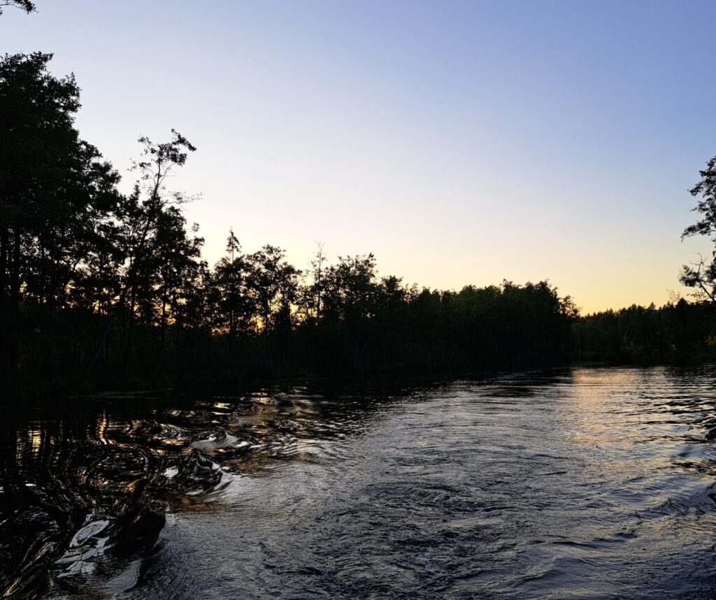 Rejs po Dolinie Rospudy - spektakularny zachód słońca nad rzeką z odbiciem promieni w wodzie podczas wycieczki w Augustowie